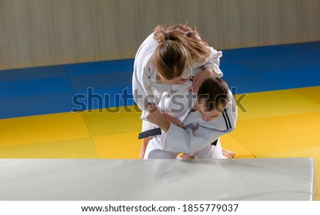 Adult black belt judoka demonstrating morote seoi nage technique on young female student Royalty-Free Stock Photo #1855779037