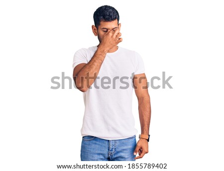 Young latin man wearing casual clothes tired rubbing nose and eyes feeling fatigue and headache. stress and frustration concept. 
