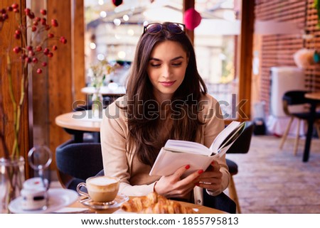 Portrait of beautiful woman reading a book while relaxing in the cafe.  Royalty-Free Stock Photo #1855795813