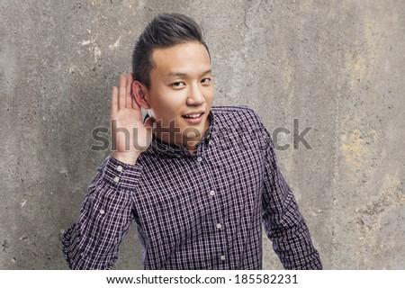 Handsome young asian man trying to hear something