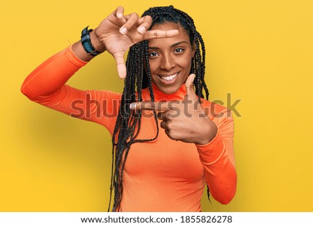 African american woman wearing casual clothes smiling making frame with hands and fingers with happy face. creativity and photography concept. 