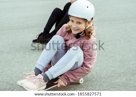 Happy teenagers boy and girl having fun skateboarding in street in helmets