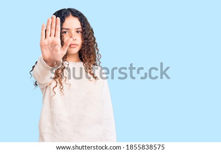 Beautiful kid girl with curly hair wearing casual clothes doing stop sing with palm of the hand. warning expression with negative and serious gesture on the face. 