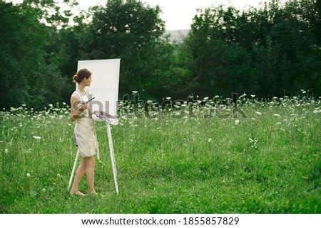 Woman artist with canvas on nature paints a picture