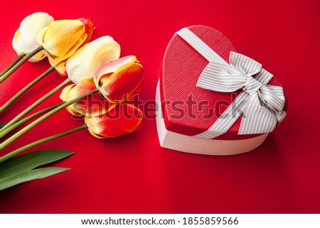bouquet of tulips and a red box in the form of a heart with a bow, a red background