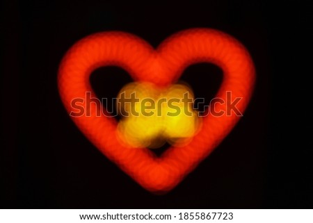 Defocused photography of the illuminated heart on the city street. Romantic concepts of modern lifestyles. Red-light in night. 24 hours open