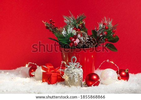 Christmas card composition with snow and Christmas tree branches decoration and present boxes on the red background. Xmas and new year celebration