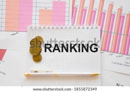 ranking text written on a white notepad with coins lie nearby and pink financial statements. High quality photo