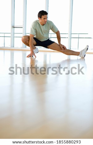 Vertical shot of a fitness man doing stretching exercises at the gym.