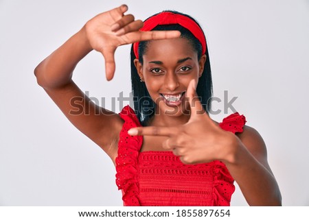 Young african american woman wearing casual clothes smiling making frame with hands and fingers with happy face. creativity and photography concept. 
