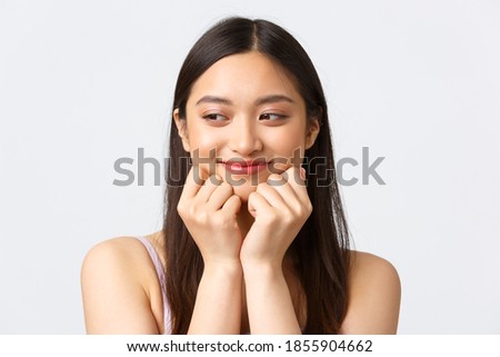 Concept of beauty, fashion and makeup products advertisement. Close-up portrait of adorable romantic asian woman, looking dreamy aside as imaging or remember lovely moment, white background