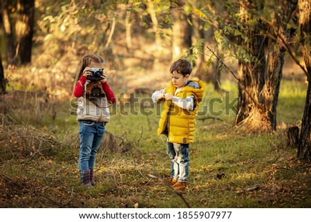 cute boy and girl 4 years old play with an old film camera and take pictures of each other