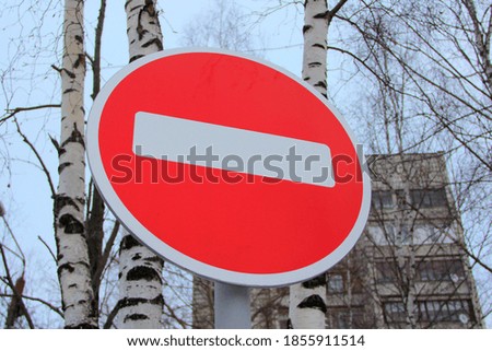 Red round road sign with white stripe prohibiting movement against the bright sky and trees. Do not enter. concept of prohibition, dead end, hopelessness and stop.