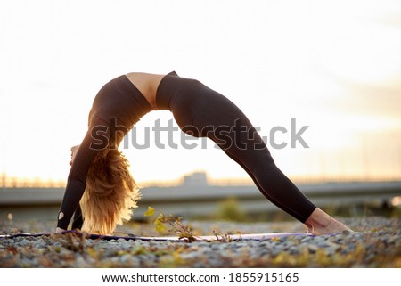 young sporty woman is practicing yoga, beautiful female doing Glute Bridge exercise, in dvi pada pithasana pose, working out outdoors