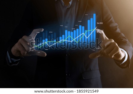 Business man holding holographic graphs and stock market statistics gain profits. Concept of growth planning and business strategy. Display of good economy form digital screen Royalty-Free Stock Photo #1855921549