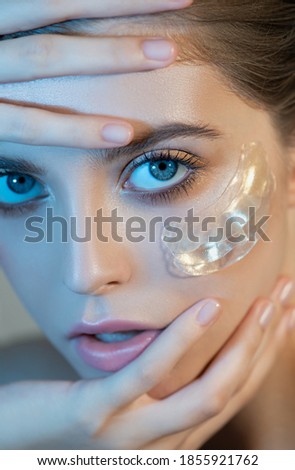 Beautiful young woman's face with light makeup and  gold eye patches mask on her face, closeup. Portrait of beauty model with natural make-up cares about her skin. Selective focus.