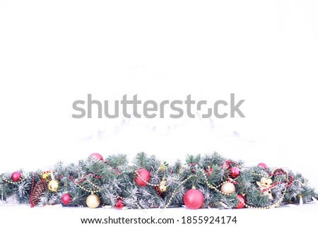 Christmas holiday background. Silver and red bauble hanging from a decorated on tree with bokeh and snow, copy space.