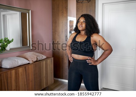 attractive afro american black female engaged in fitness at home, overweight woman is stretching and doing various sport exercises