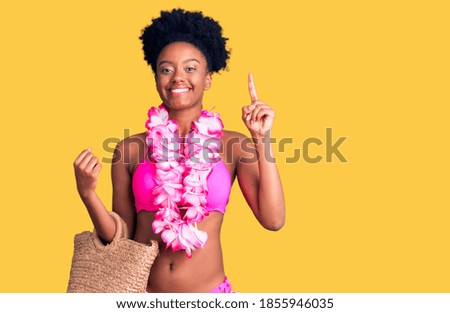 Young african american woman wearing bikini and hawaiian lei surprised with an idea or question pointing finger with happy face, number one 