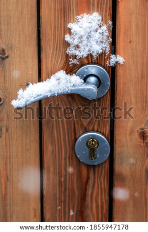 Snow falling on door handle outdoors, specific season image, close up view, winter time concept 