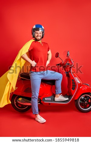 super hero biker man going at party, excited, stand next to motorcycle, using super powers to move fast isolated over red background
