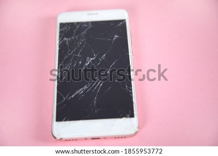 broken phone on the pink table background