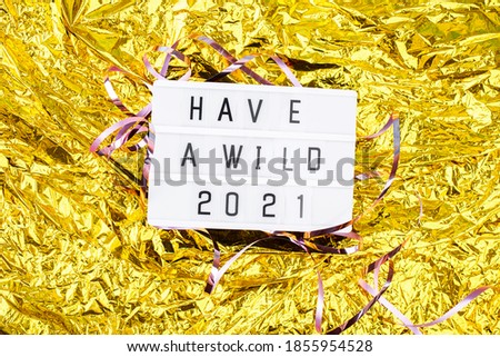 Light box with an inscription have a wild 2021 on a bright gold background. New years content