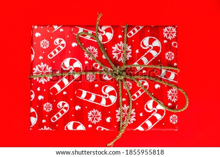 Big red Christmas gift with a bow on a red background.