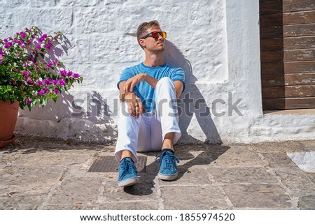 Young man sitting by the trulli houses in Alberobello, province Bari, region Puglia, Italy. Beautiful Italy, Bari region.