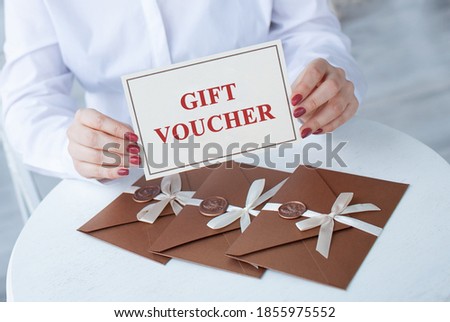 close-up photo of gift voucher in hands. bronze invitation envelope with a wax seal, a gift certificate on table