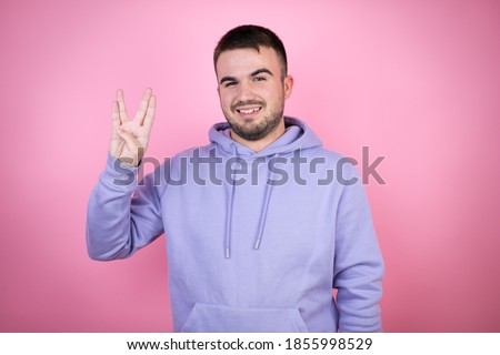 Young handsome man wearing casual sweatshirt over isolated pink background doing hand symbol