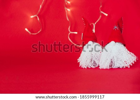 Red Christmas gnomes on a red background with lights. Christmas concept. Copy space