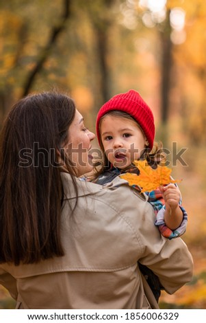 mother with kid in the autumn forest walking together girl in the red cap