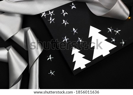 Black and white christmas mock up for greetings with white toys, silver ribbon, stars on black background