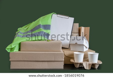 Workplace delivery service with a lot of boxes, take away coffee and green vest.