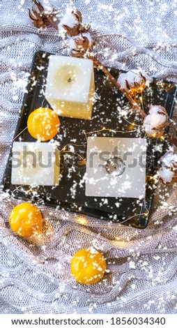 Inspiration winter cozy still life composition with cotton, tangerines, candles and snowflakes on cozy gray plaid. Concept of Color of the Year 2021 with bright illuminating yellow and gray colours.