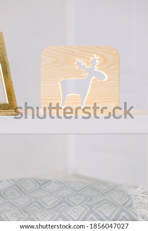 image of decorative wooden night lamp with deer picture, on light table, at cozy room interior