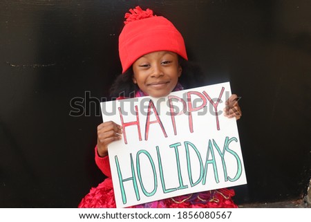 Young smiling child holding Happy Holidays sign black background
