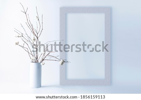 Template with photo frame on white background. Bouquet of Snowberry with white branches in a vase. Mock up in high key.