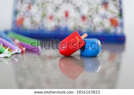 Dreidels (spinning top) and colorful candles beside a Menorah candelabra on  Hanukkah Jewish holiday.
