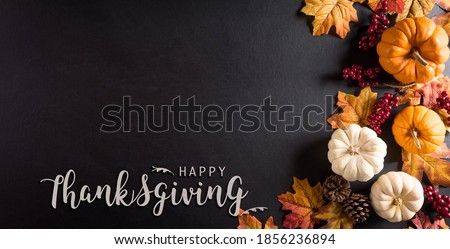 Thanksgiving background decoration from dry leaves,red berries and pumpkin on blackboard background. Flat lay, top view for Autumn, fall, Thanksgiving concept.
