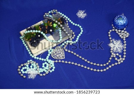 Christmas concept. Beautiful gift wrap. Celebration. snowflakes. Spruce cones and needles. tree glass ball. Beads. Place for text. On a blue background.
