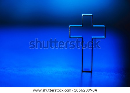 Silhouette of christian cross on blue background, soft bokeh lights background. Copy space. Church worship, salvation concept. Faith symbol in Jesus Christ. Holy cross for Christmas, Easter day.