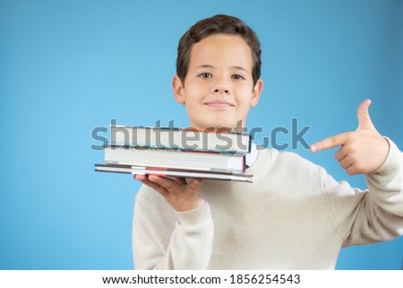 Boy with books for an education portrait - isolated over a blue background