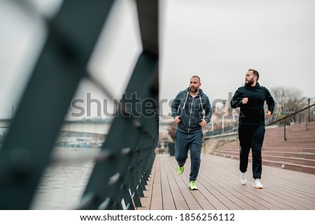 Male friends running in autumn day 