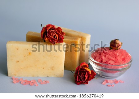 Natural handmade soap, pink salt for bath, dried roses on a blue background. The concept of body care. Spa organic cosmetics. Copy space.