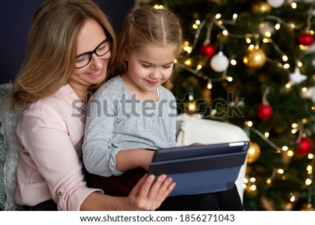 Grandmother with granddaughter using tablet in Christmas time                               