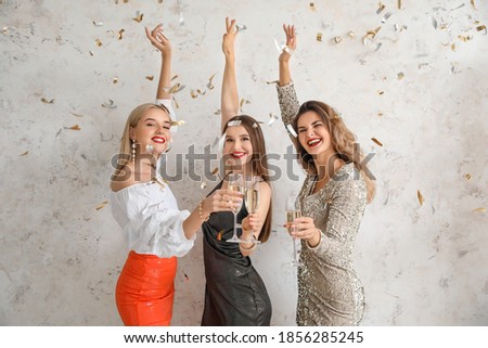 Young women with glasses of tasty champagne on light background