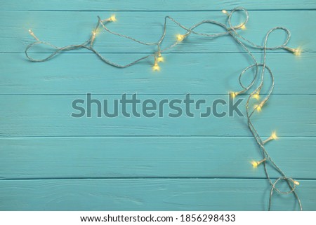 Christmas garland lights on blue wooden background. Top view.