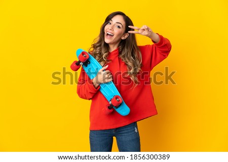 Young caucasian woman isolated on yellow background with a skate with happy expression
